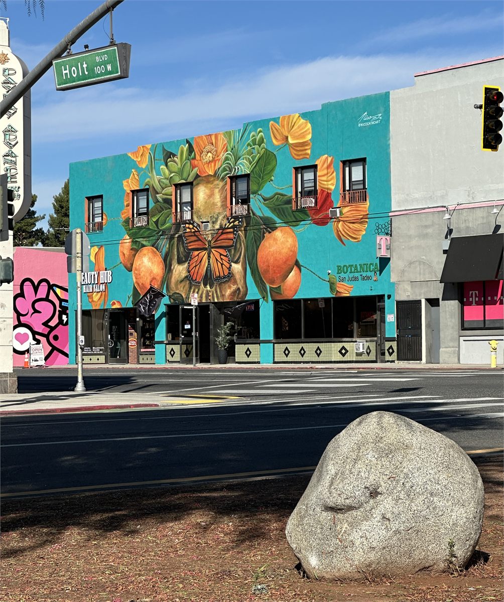 A completed O-Town Walls mural beside the Holt Boulevard street sign in Downtown Ontario
